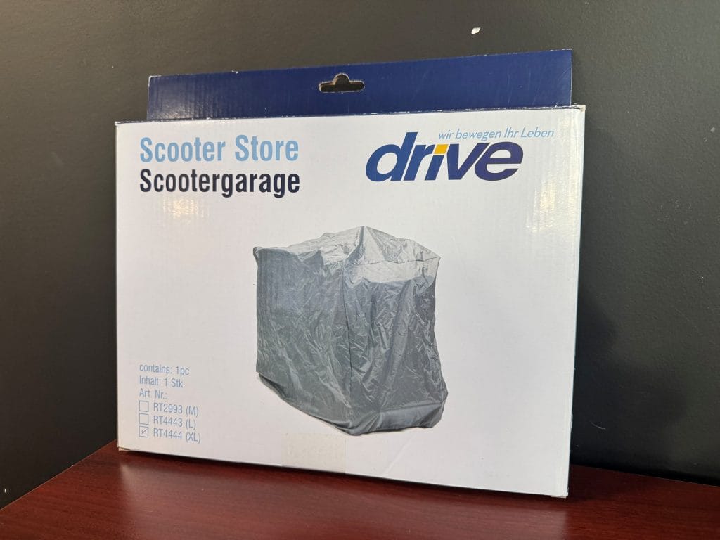 Grijze waterdichte scootmobiel garagehoes Drive voor buiten- en bergingbescherming, getoonde XL-matenverpakking op tafel.