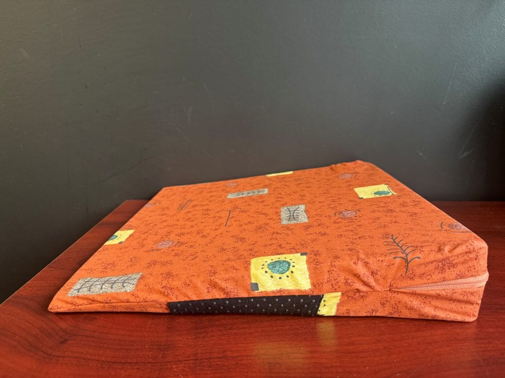 Zijaanzicht Wigkussen Sissel® Sit Basic in oranje print met rits; steunend zitkussen voor rechte zithouding (tweedekans).